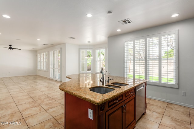 kitchen with dishwasher, decorative light fixtures, light stone counters, sink, and a center island with sink