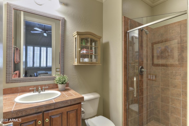 bathroom with vanity, toilet, a shower with door, and ornamental molding