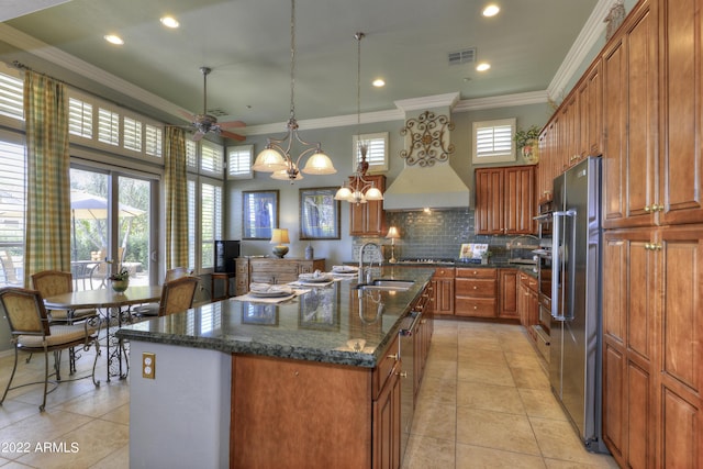 kitchen with a center island with sink, hanging light fixtures, high end fridge, and sink