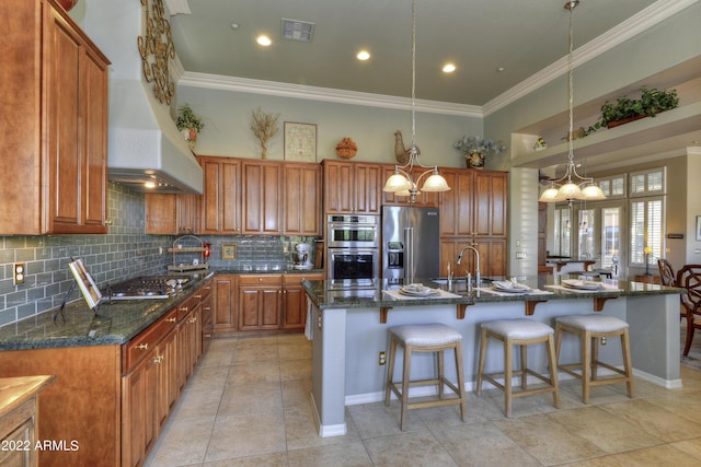 kitchen featuring decorative backsplash, stainless steel appliances, decorative light fixtures, dark stone countertops, and an island with sink