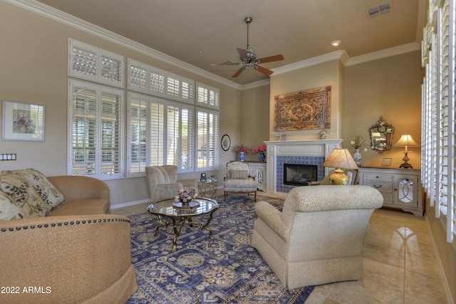 tiled living room featuring ceiling fan, ornamental molding, and a tiled fireplace