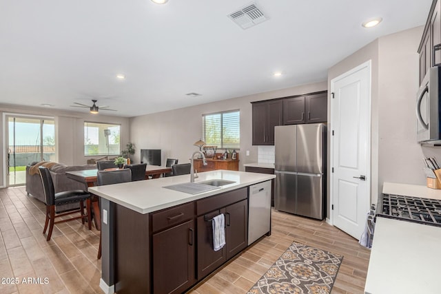 kitchen featuring dark brown cabinets, stainless steel appliances, sink, and a center island with sink