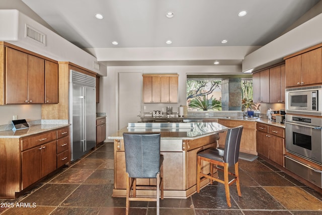 kitchen with a breakfast bar area, built in appliances, and a kitchen island