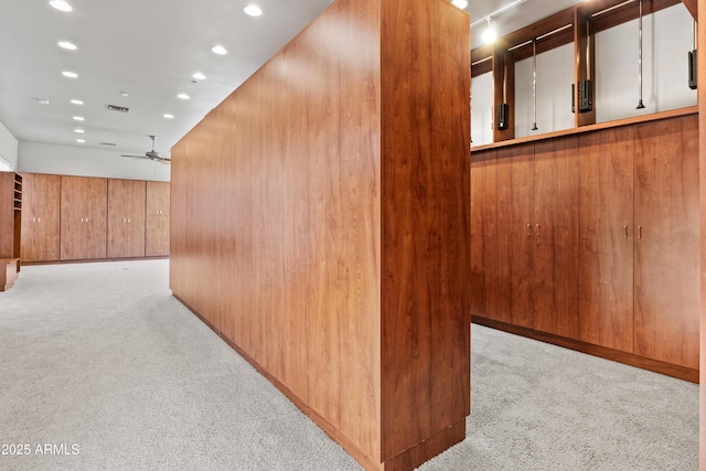 hallway featuring light carpet and wood walls