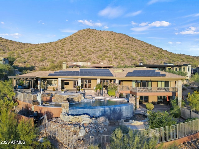 rear view of house with a fenced in pool, a mountain view, and solar panels