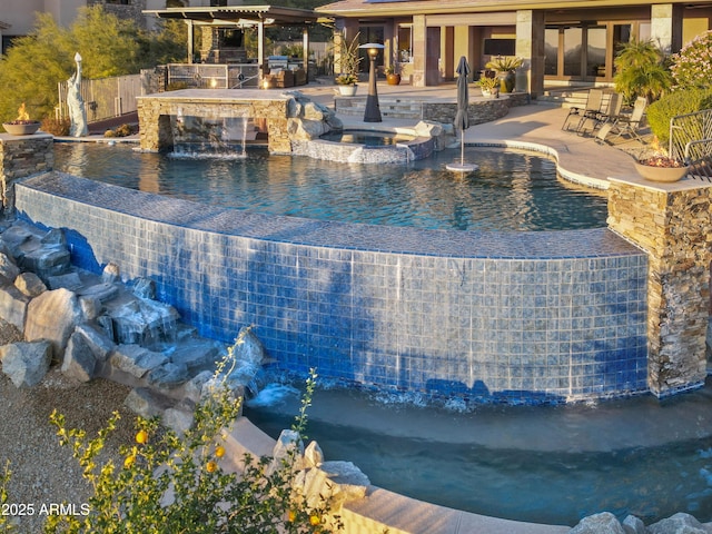 view of swimming pool featuring an in ground hot tub, pool water feature, area for grilling, and a patio area