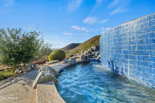 view of swimming pool with pool water feature and a mountain view