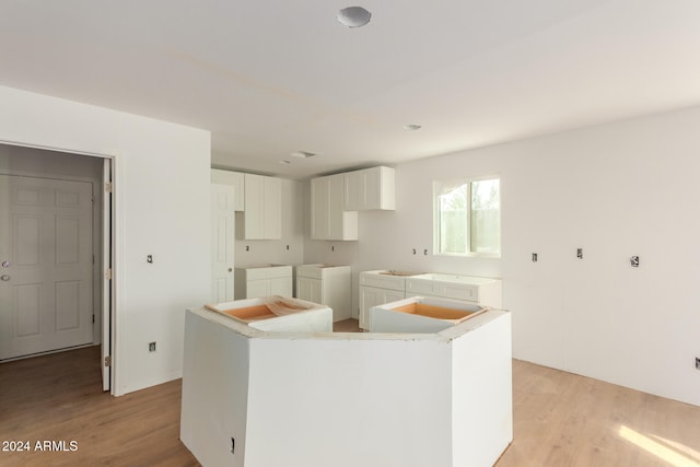 kitchen with light wood-type flooring, white cabinetry, and a kitchen island