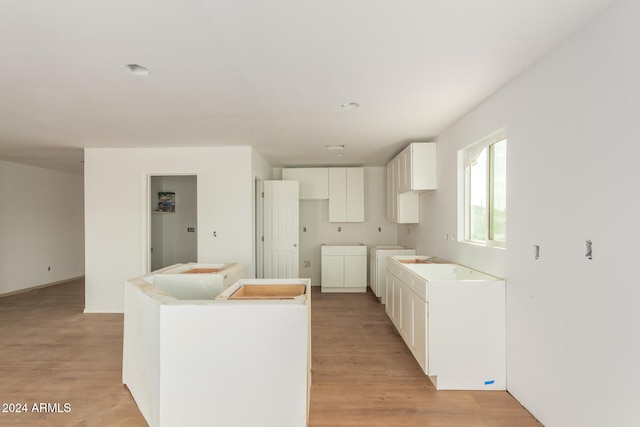 kitchen featuring washing machine and clothes dryer, a center island, white cabinets, and light hardwood / wood-style floors