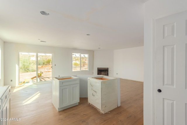 kitchen with white cabinetry, a center island, and light wood-type flooring