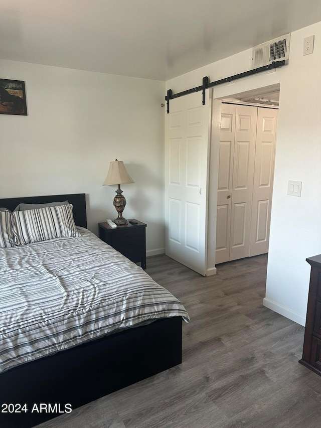 bedroom featuring dark hardwood / wood-style floors, a closet, and a barn door