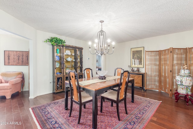 dining area featuring a textured ceiling, dark hardwood / wood-style floors, and a chandelier