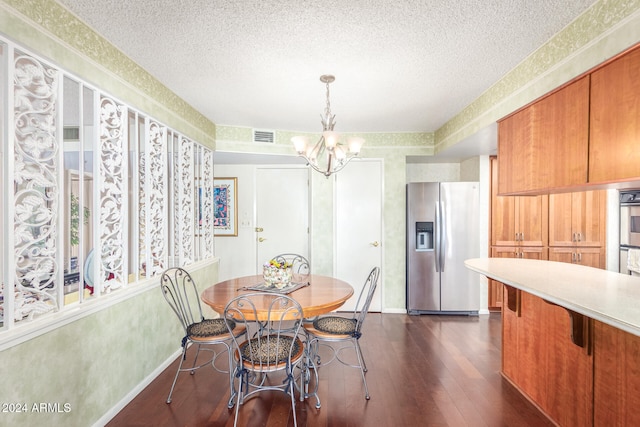 dining area featuring dark hardwood / wood-style floors, a textured ceiling, and an inviting chandelier