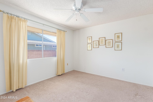 unfurnished room with ceiling fan, a textured ceiling, and carpet