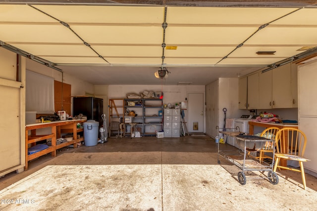 garage with a garage door opener, washer and dryer, and black refrigerator