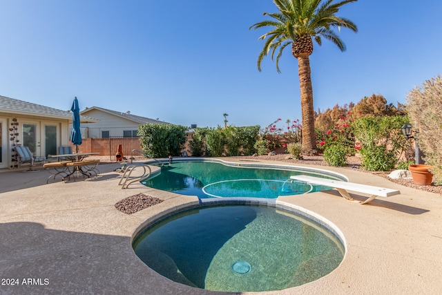 view of pool with a diving board, an in ground hot tub, and a patio area