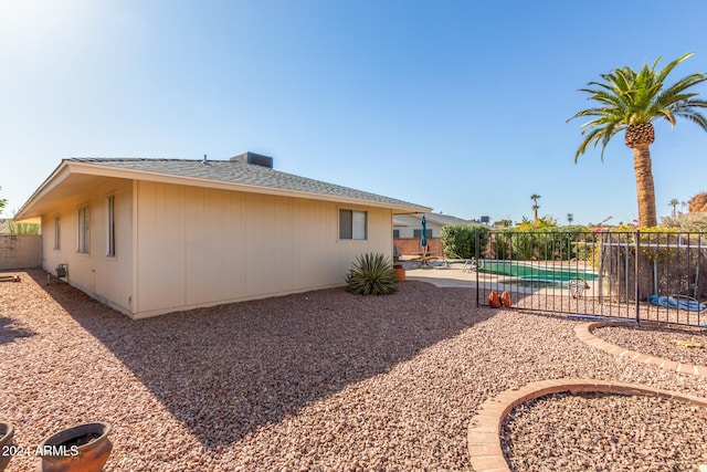 rear view of house featuring a fenced in pool and a patio