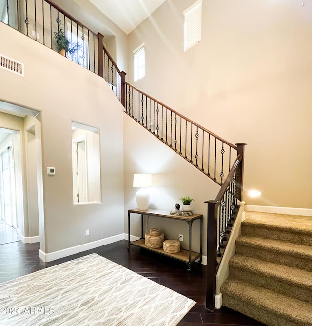 stairs featuring a towering ceiling and hardwood / wood-style floors