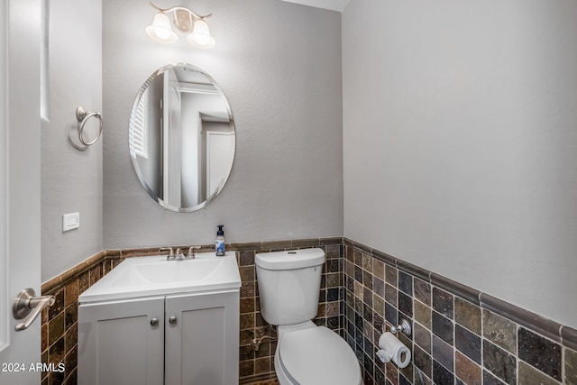 bathroom featuring vanity, toilet, and tile walls