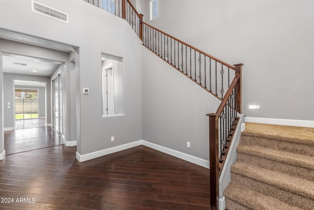 staircase with a towering ceiling and hardwood / wood-style floors