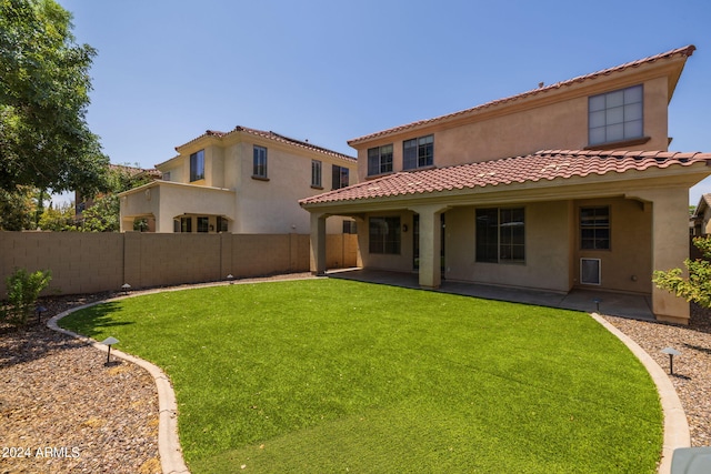 back of property with a lawn and a patio