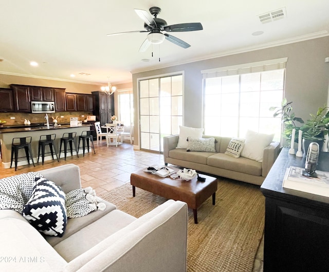 tiled living room with crown molding, sink, and ceiling fan with notable chandelier