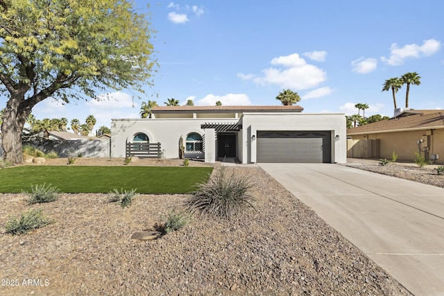 mediterranean / spanish-style home featuring stucco siding, fence, a garage, driveway, and a front lawn