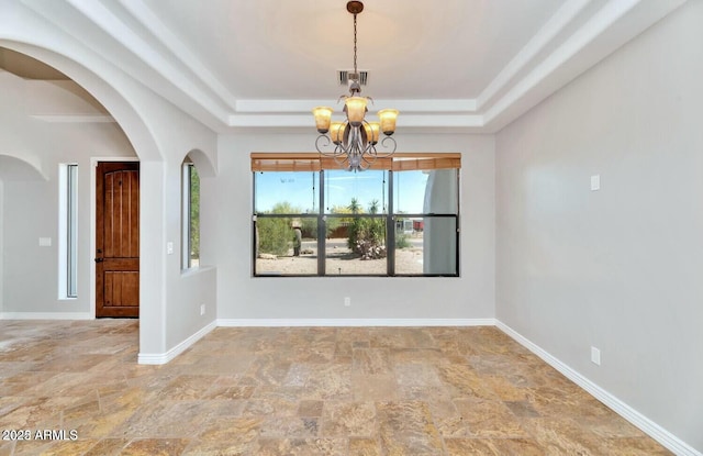 spare room with a notable chandelier and a tray ceiling