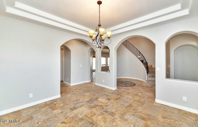 unfurnished room with a tray ceiling and a notable chandelier