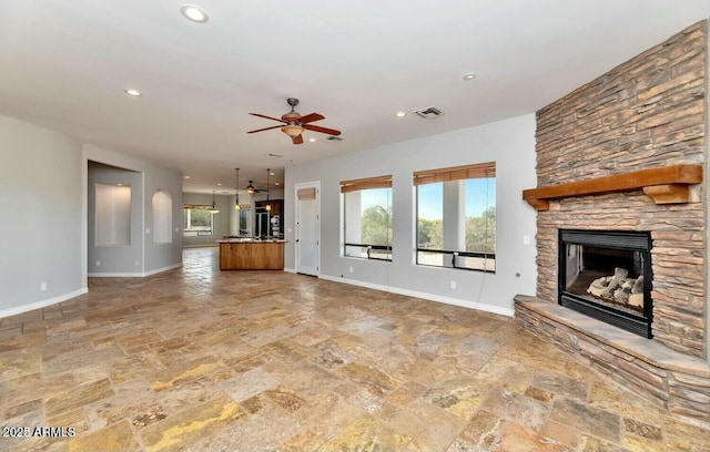 unfurnished living room with ceiling fan, a healthy amount of sunlight, and a fireplace