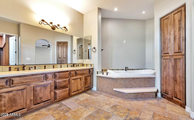 bathroom featuring a relaxing tiled tub and vanity