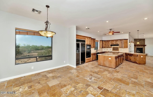 kitchen featuring ceiling fan, decorative light fixtures, a kitchen island, and black appliances