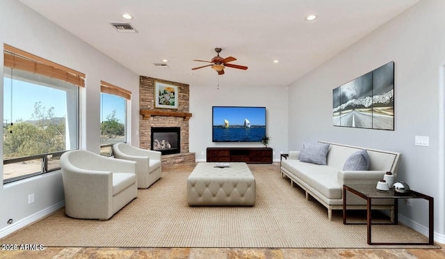 living room featuring a stone fireplace and ceiling fan