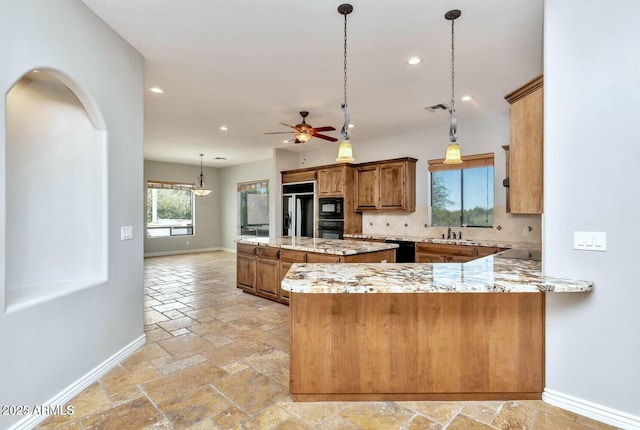 kitchen with decorative light fixtures, black appliances, sink, backsplash, and kitchen peninsula