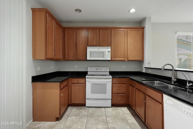 kitchen with sink, white appliances, light tile patterned floors, and dark stone counters