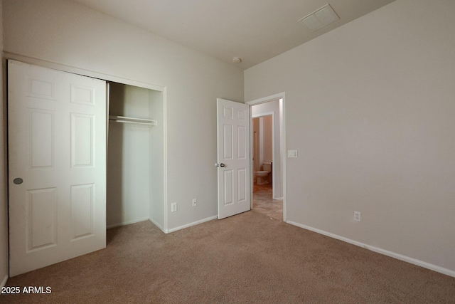 unfurnished bedroom with a closet and light colored carpet