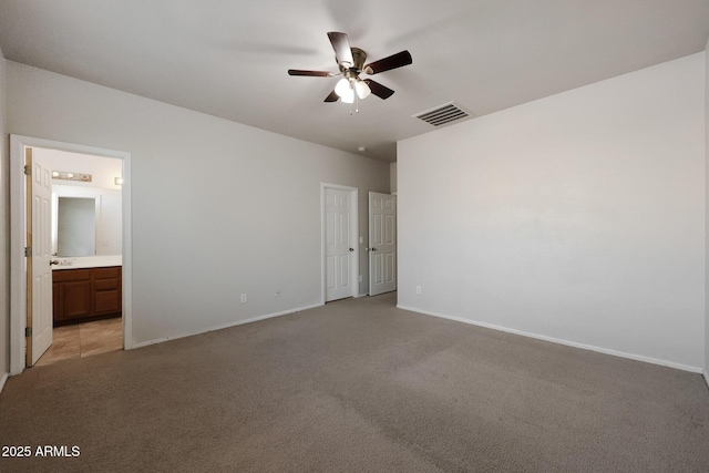 unfurnished bedroom with ceiling fan, light carpet, and connected bathroom