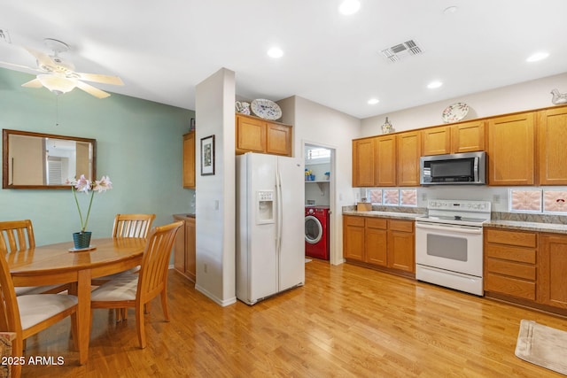 kitchen with white appliances, ceiling fan, light wood-type flooring, light stone countertops, and washer / dryer