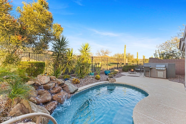 view of swimming pool with pool water feature, area for grilling, exterior kitchen, and a patio area