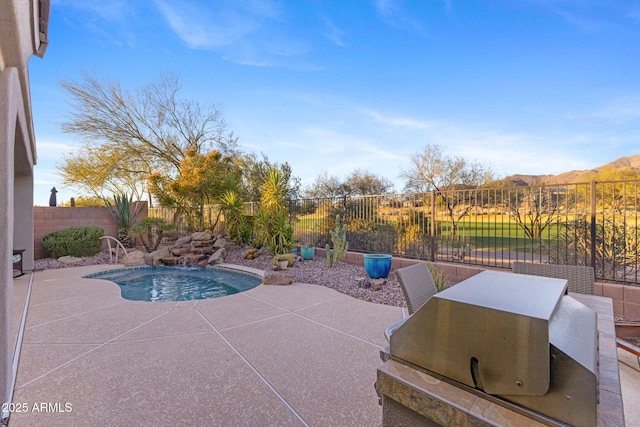 view of patio with grilling area, a fenced in pool, and a mountain view