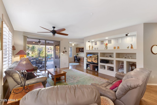 living room featuring light wood-type flooring and built in features