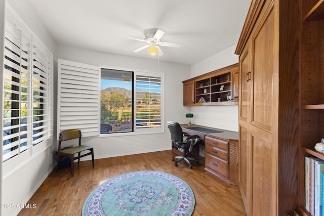 office featuring built in desk, ceiling fan, and light hardwood / wood-style flooring