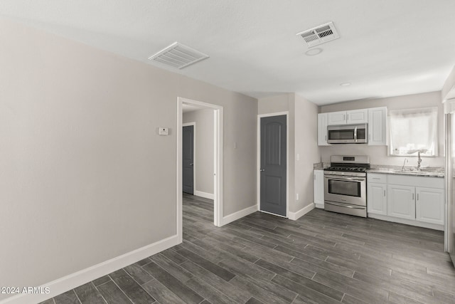 kitchen with appliances with stainless steel finishes, dark hardwood / wood-style flooring, white cabinetry, and sink