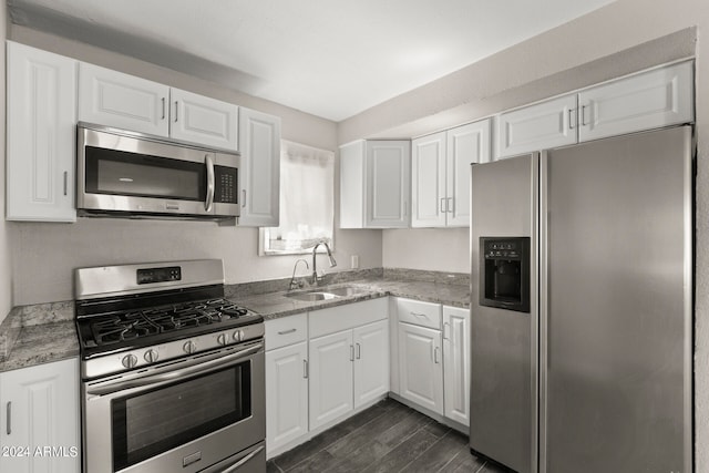 kitchen featuring dark hardwood / wood-style floors, appliances with stainless steel finishes, white cabinets, sink, and stone counters