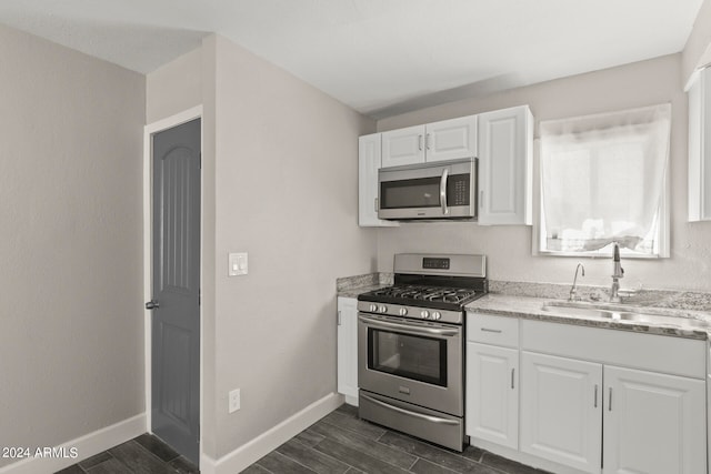 kitchen featuring light stone countertops, dark wood-type flooring, stainless steel appliances, sink, and white cabinets