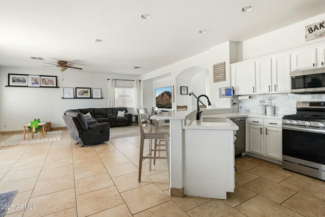 12209 W Washington St, Avondale, AZ 85323 - kitchen with appliances with stainless steel finishes, a sink, a peninsula, arched walkways, and a ceiling fan