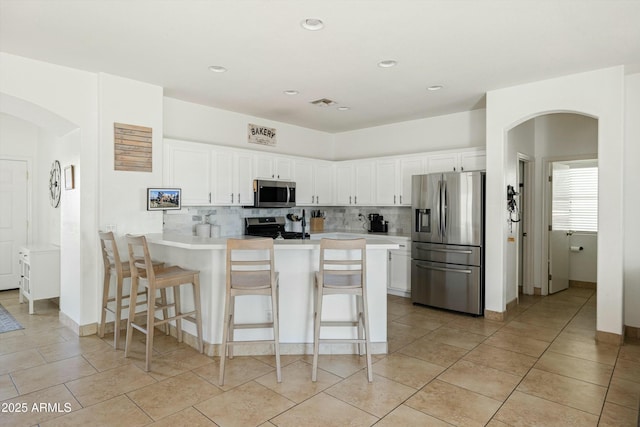 12209 W Washington St, Avondale, AZ 85323 - kitchen featuring stainless steel appliances, arched walkways, a peninsula, decorative backsplash, and recessed lighting