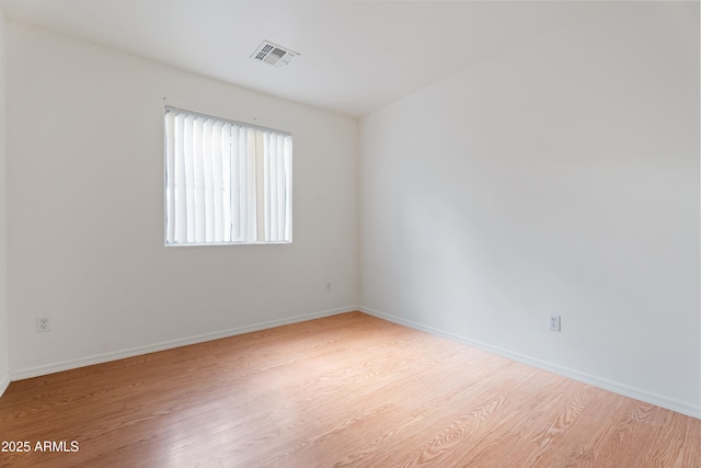 unfurnished room featuring light wood-style floors, visible vents, and baseboards