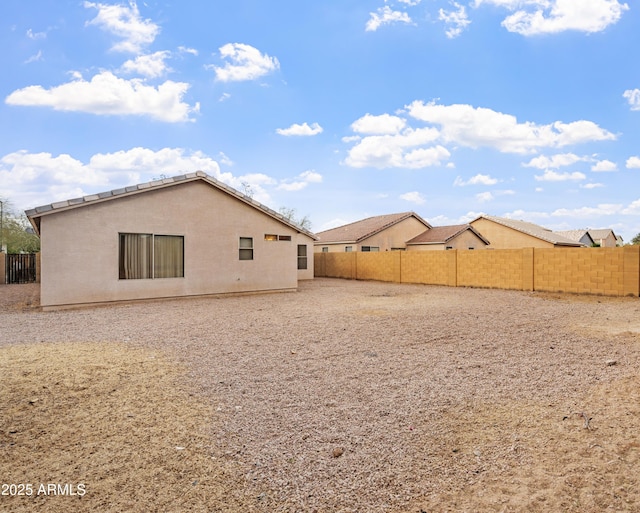 rear view of house featuring stucco siding and a fenced backyard