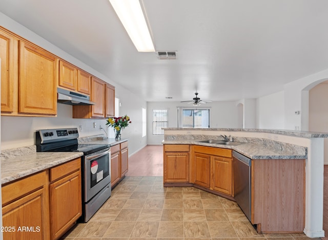 kitchen with visible vents, arched walkways, a sink, under cabinet range hood, and appliances with stainless steel finishes